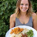 Una persona sonriendo con un plato de comida personalizada, representando planes de alimentación a medida.